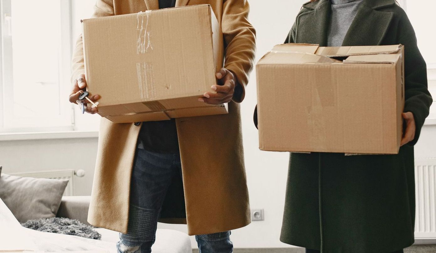 Happy couple carrying moving boxes into their new home, symbolizing a fresh start.