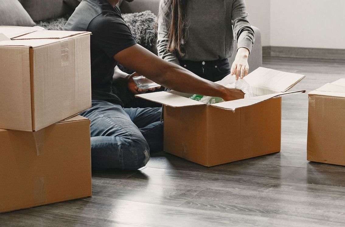 Happy couple unpacking moving boxes in their new apartment living room.