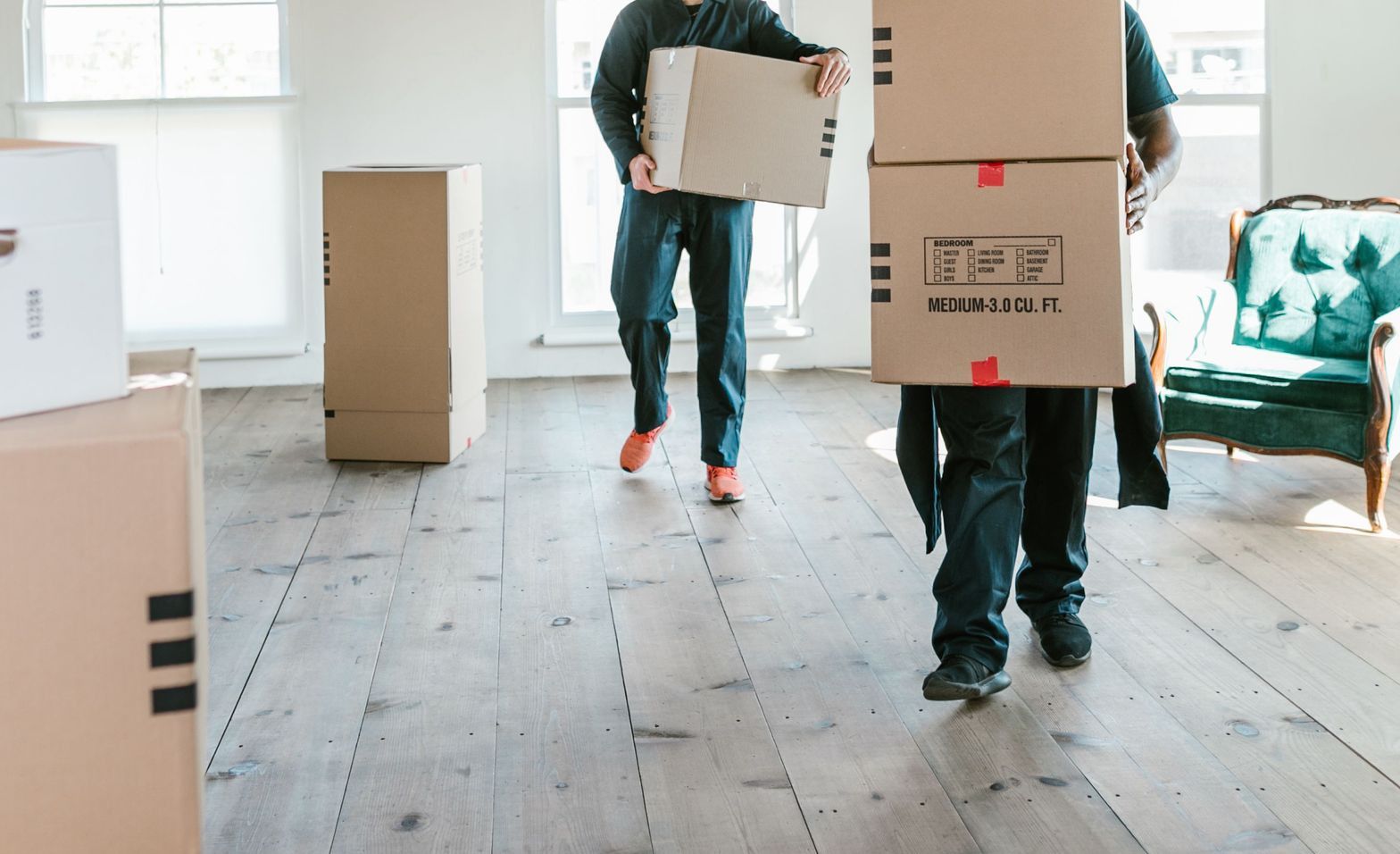 Two movers carrying boxes in a sunlit room, ready to assist with relocation.